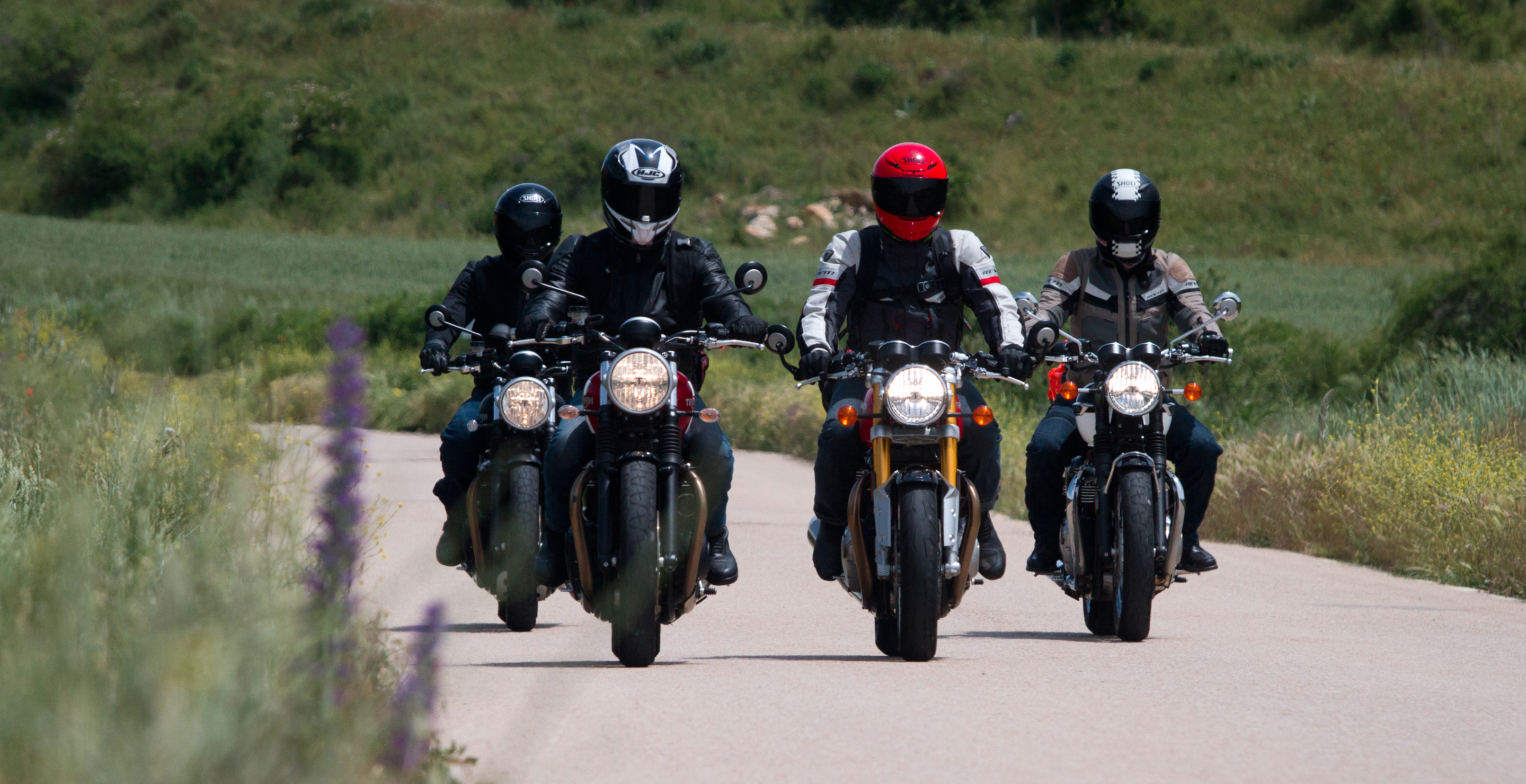 Motos Triumph en marcha de ruta por una carretera y fondo de campo