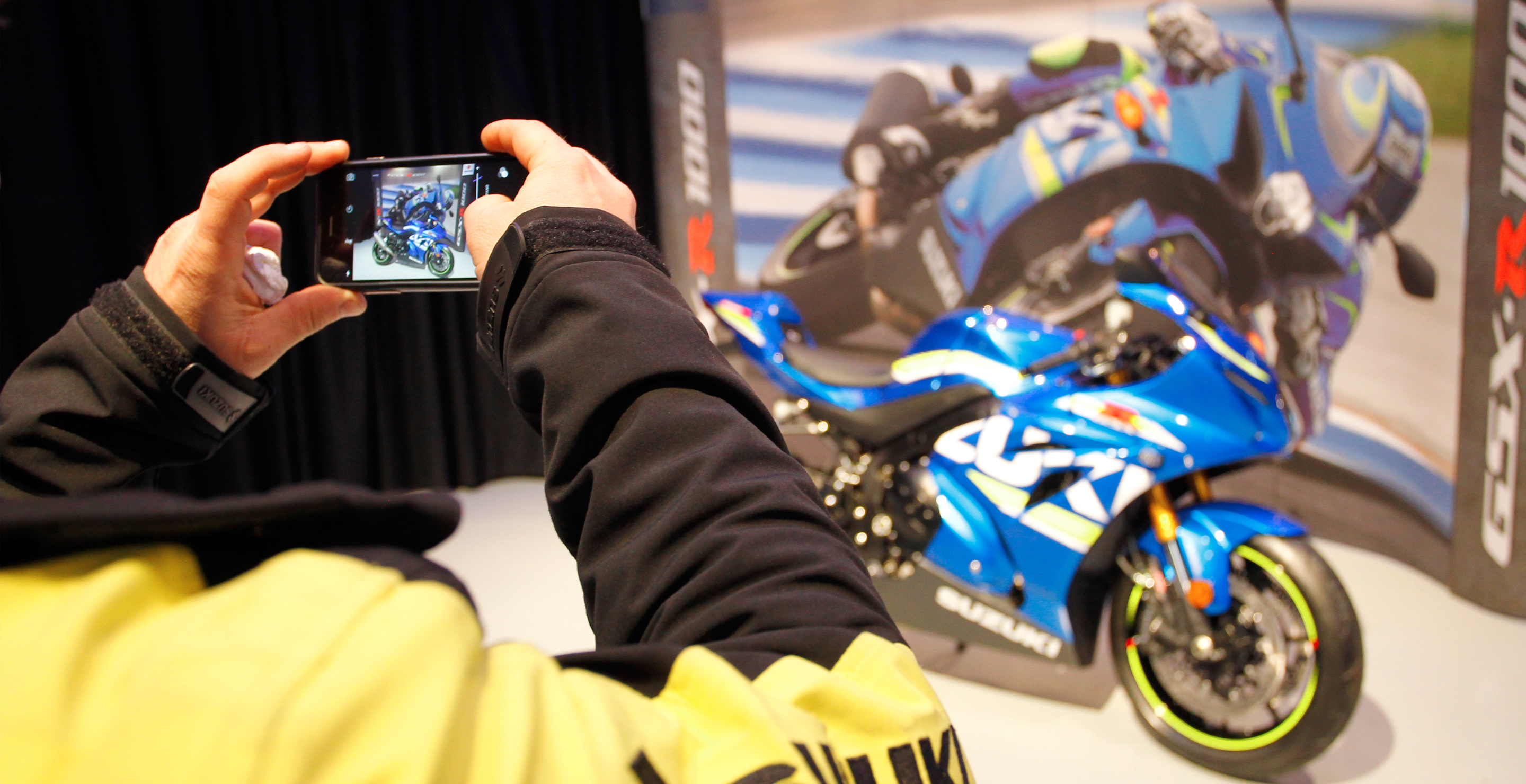 Persona haciendo foto con el móvil a uma moto Suzuki